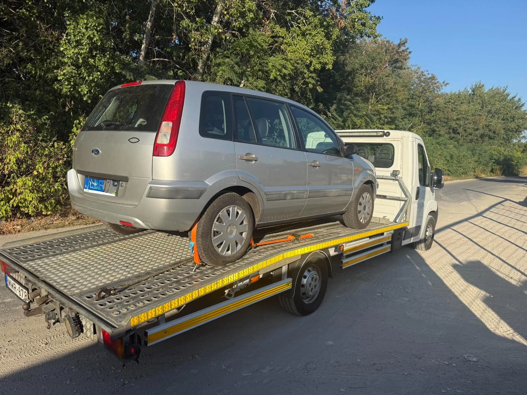 Ezüst autó hevederrel rögzítve a platón
