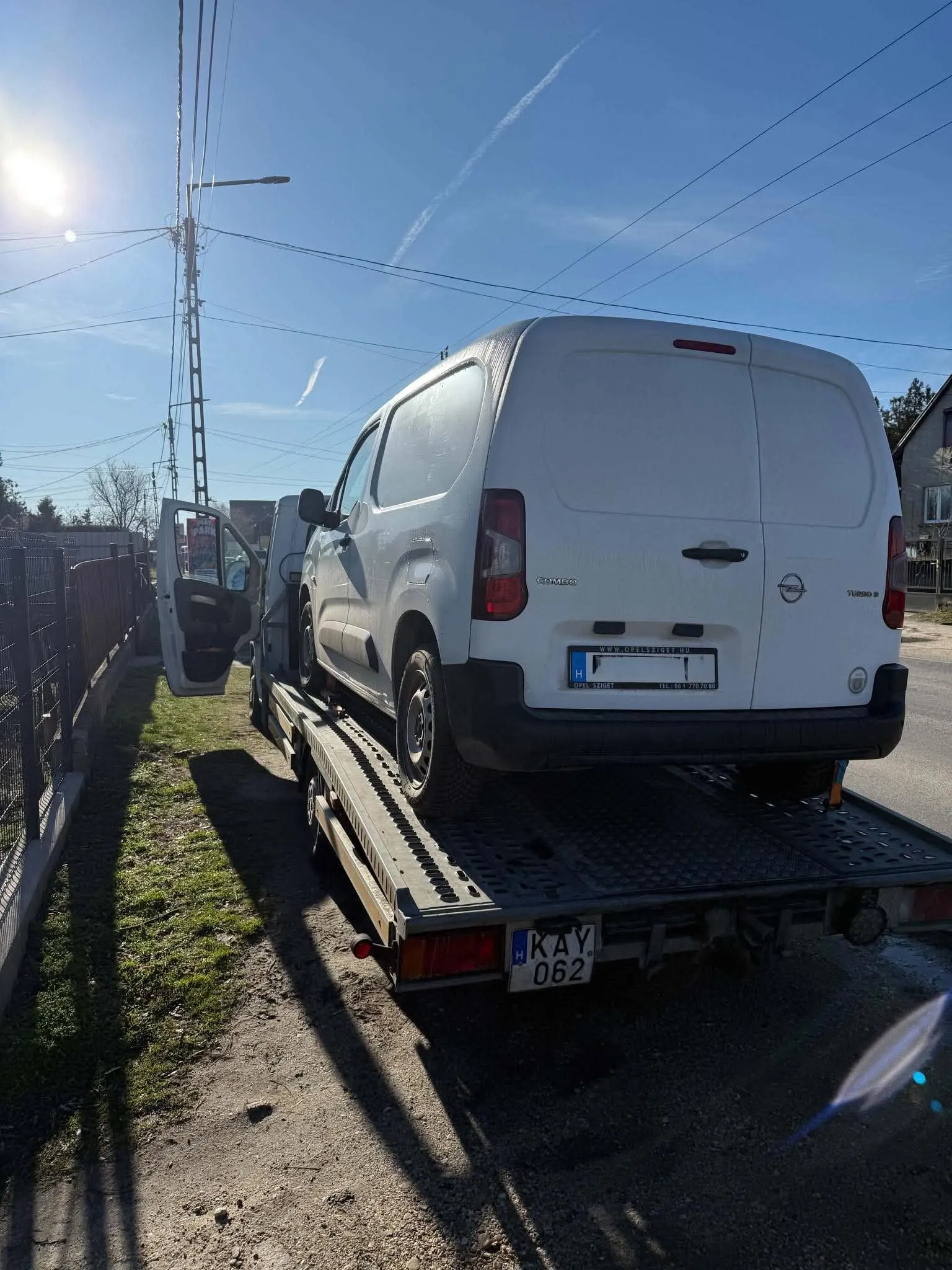 Fehér furgon a platós vontatón